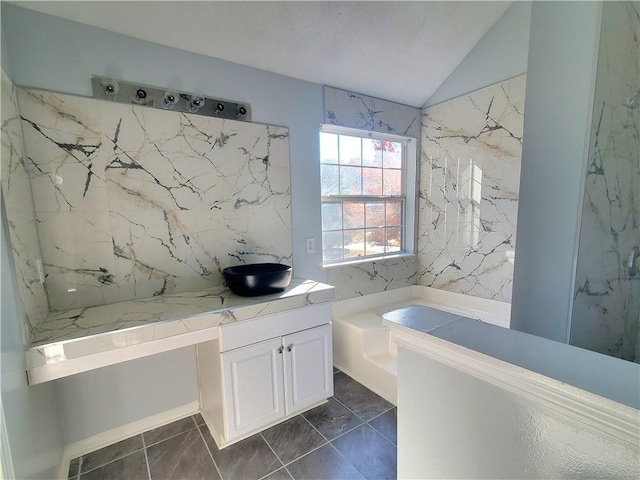 bathroom featuring vanity, lofted ceiling, and a tub