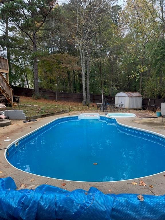 view of swimming pool with a storage unit, a patio area, and a wooden deck