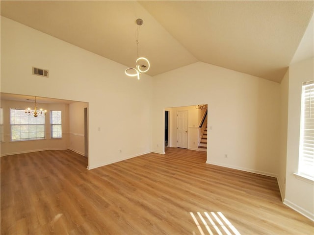 unfurnished room with hardwood / wood-style floors, vaulted ceiling, and a notable chandelier