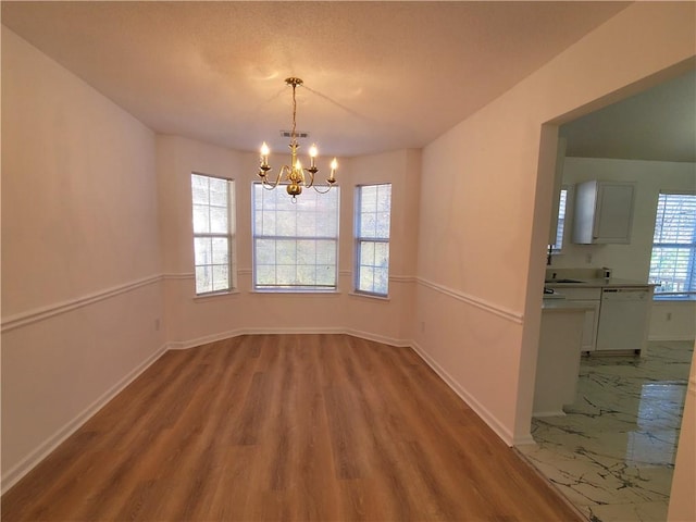 unfurnished dining area with light wood-type flooring and a notable chandelier