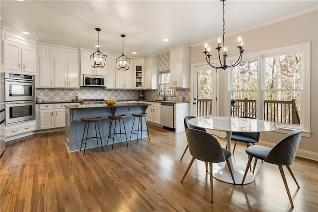 dining area with a notable chandelier, dark wood finished floors, recessed lighting, crown molding, and baseboards