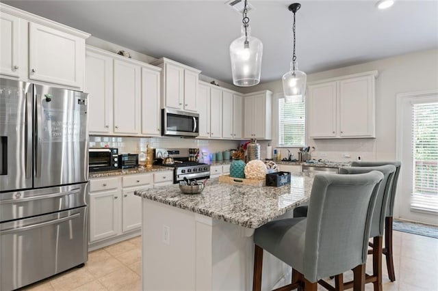 297 Aylesbury Blvd, Mcdonough, GA 30252 - kitchen featuring appliances with stainless steel finishes, a center island, a kitchen bar, light stone counters, and decorative backsplash