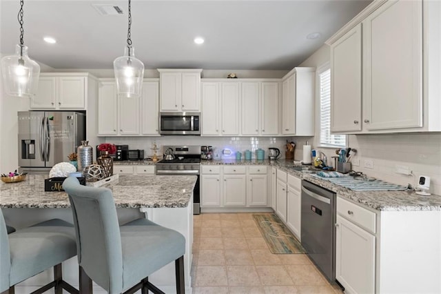 297 Aylesbury Blvd, Mcdonough, GA 30252 - kitchen with appliances with stainless steel finishes, tasteful backsplash, white cabinetry, a breakfast bar, and pendant lighting