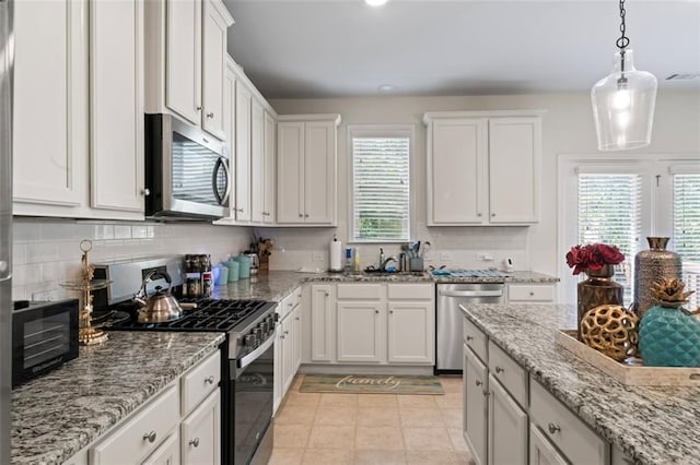 297 Aylesbury Blvd, Mcdonough, GA 30252 - kitchen with appliances with stainless steel finishes, white cabinetry, tasteful backsplash, decorative light fixtures, and light stone counters