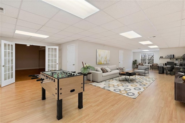 playroom with a drop ceiling, french doors, and light wood-type flooring