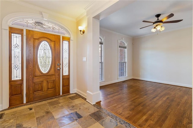 entryway with crown molding, stone finish floor, a ceiling fan, visible vents, and baseboards
