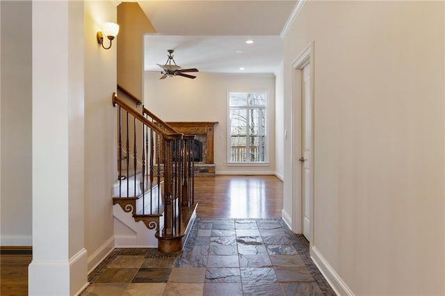 corridor featuring baseboards, crown molding, recessed lighting, stairway, and stone tile floors
