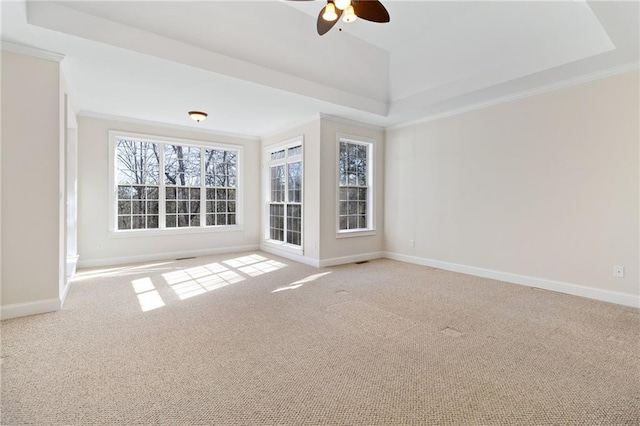 empty room featuring ceiling fan, visible vents, carpet flooring, a raised ceiling, and baseboards