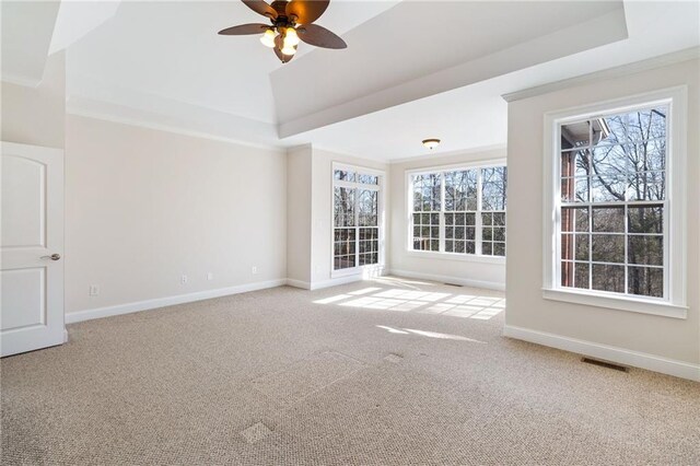 carpeted empty room with a raised ceiling, visible vents, baseboards, and ceiling fan