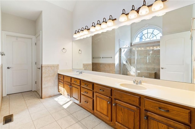 full bathroom featuring a shower stall, tile patterned floors, double vanity, and a sink