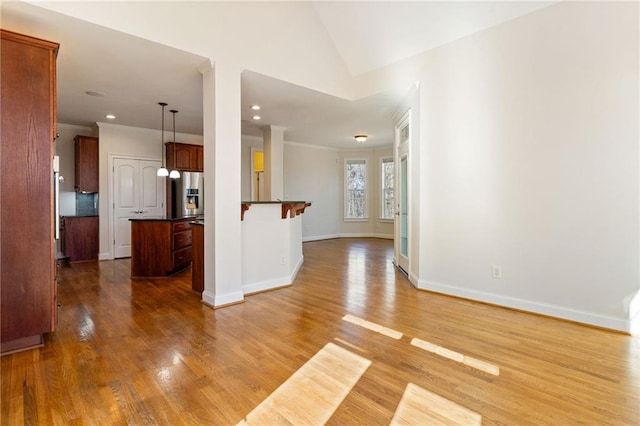 interior space featuring a center island, stainless steel refrigerator with ice dispenser, open floor plan, dark countertops, and wood finished floors