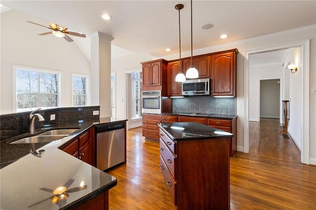 kitchen featuring sink, decorative light fixtures, appliances with stainless steel finishes, kitchen peninsula, and backsplash