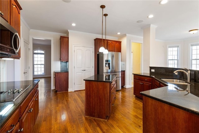 kitchen with a sink, dark wood finished floors, a healthy amount of sunlight, a center island with sink, and stainless steel appliances