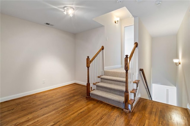 staircase with visible vents, baseboards, and wood finished floors
