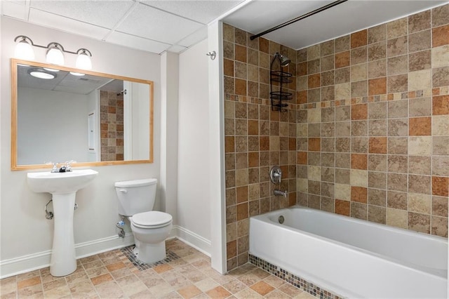 bathroom featuring a paneled ceiling, toilet, and tiled shower / bath combo