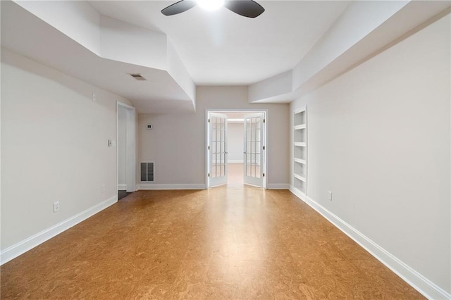 empty room with built in shelves, visible vents, baseboards, and a ceiling fan