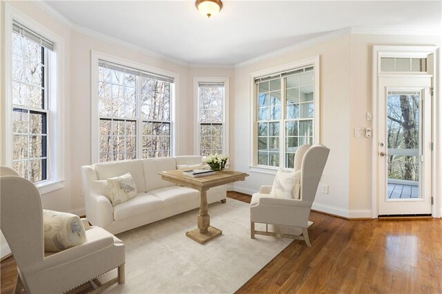 living area featuring ornamental molding, baseboards, and wood finished floors