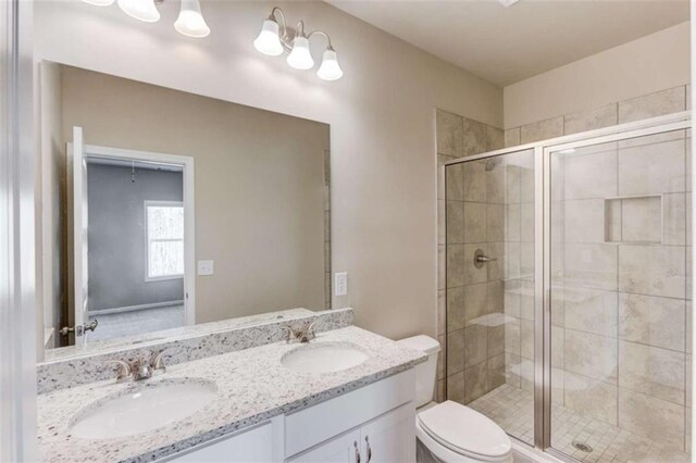 bathroom with toilet, an enclosed shower, and vanity