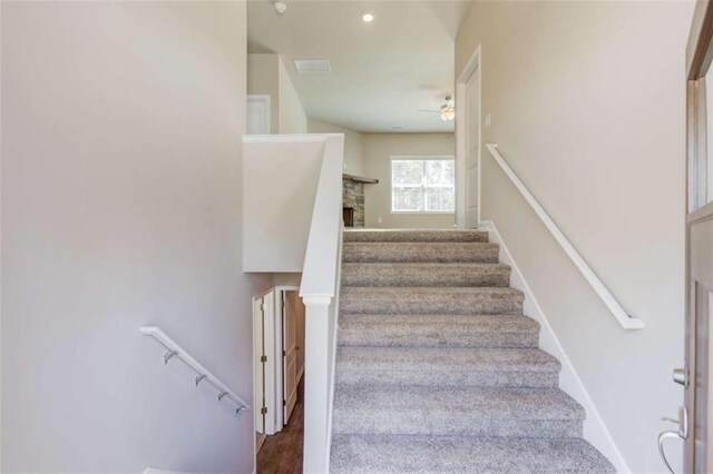 stairs with hardwood / wood-style flooring and a stone fireplace