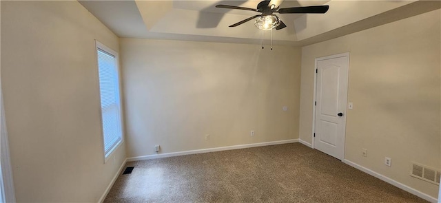 unfurnished room with ceiling fan and a tray ceiling