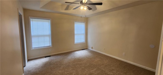 unfurnished room with a raised ceiling, carpet flooring, and ceiling fan