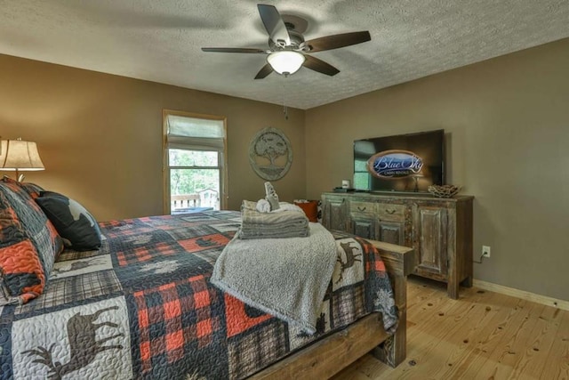 bedroom featuring ceiling fan, light wood-style floors, baseboards, and a textured ceiling