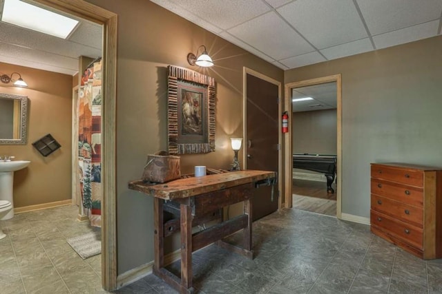 hall featuring a paneled ceiling and baseboards