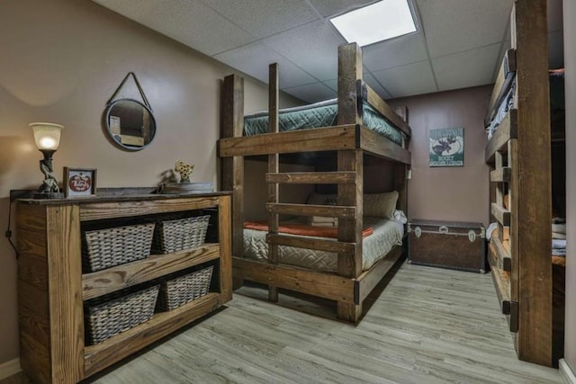 bedroom with wood finished floors and a drop ceiling