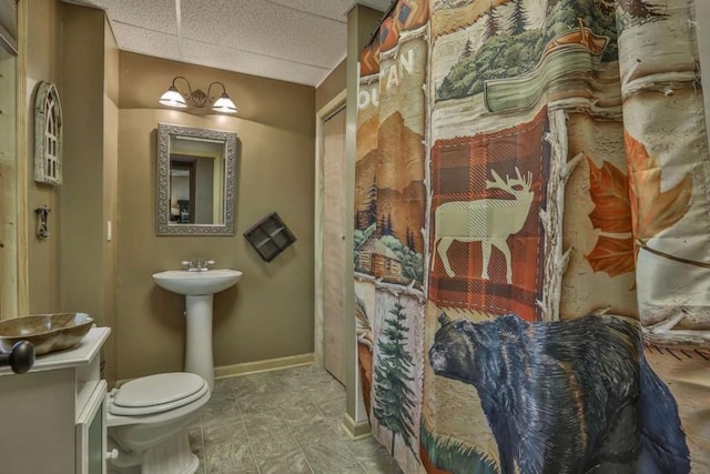 bathroom featuring baseboards, a paneled ceiling, and toilet