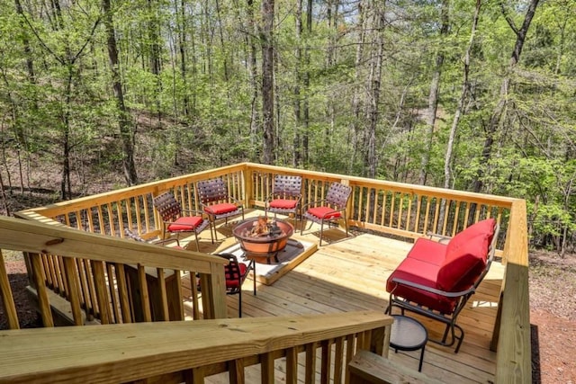 wooden deck with a wooded view and an outdoor fire pit