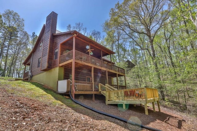 rear view of property featuring a wooden deck, a chimney, and a ceiling fan