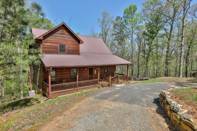 view of front facade with a porch, metal roof, and gravel driveway