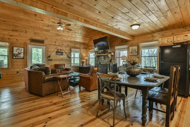 dining room featuring wood walls, wood ceiling, light wood-type flooring, and vaulted ceiling