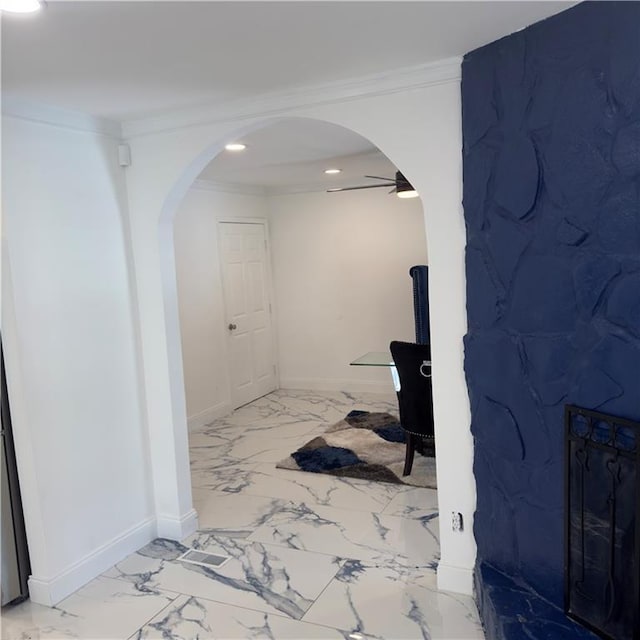 hallway featuring marble finish floor, baseboards, arched walkways, and ornamental molding