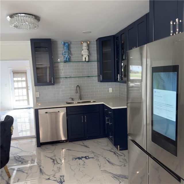 kitchen with glass insert cabinets, stainless steel appliances, light countertops, blue cabinetry, and a sink