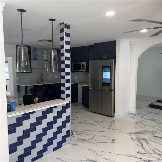 kitchen featuring stainless steel appliances, light countertops, decorative backsplash, a sink, and dark cabinetry