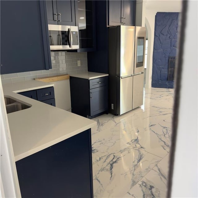 kitchen featuring marble finish floor, tasteful backsplash, stainless steel appliances, and light countertops