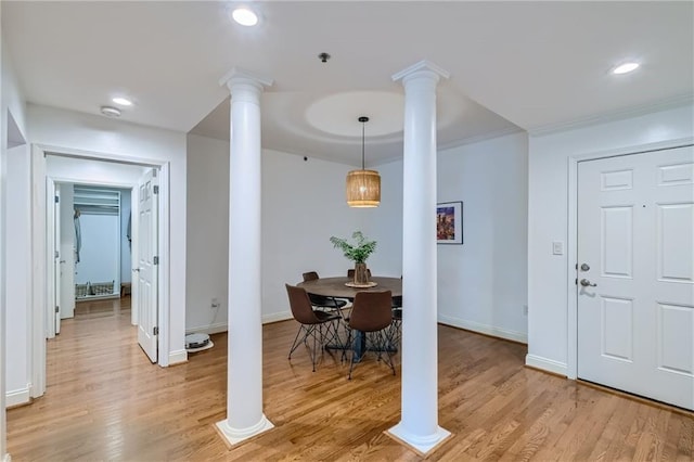 dining area featuring ornamental molding, light hardwood / wood-style flooring, and decorative columns