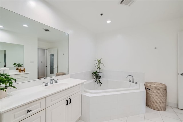 bathroom with tile patterned floors, vanity, and tiled tub