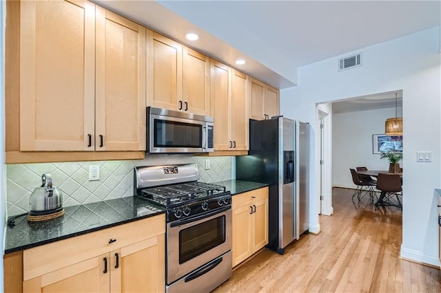 kitchen featuring appliances with stainless steel finishes, light wood-type flooring, pendant lighting, light brown cabinetry, and decorative backsplash