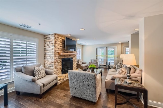 living room with dark wood-type flooring and a stone fireplace