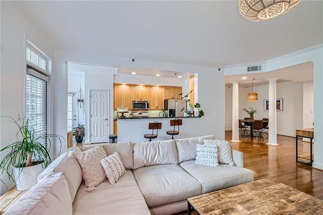 living room featuring light wood-type flooring, decorative columns, and ornamental molding