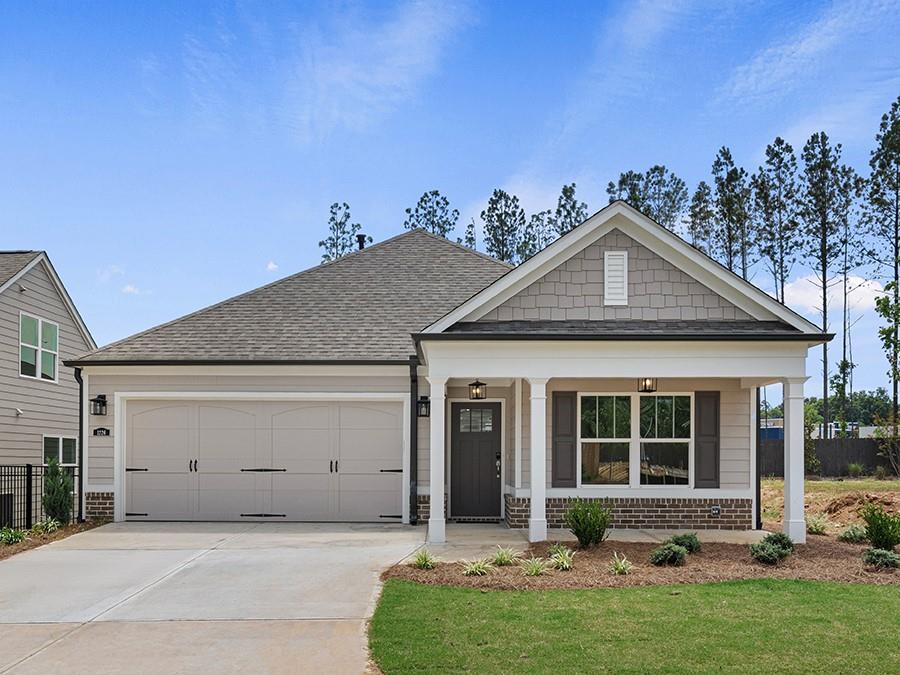 view of front of property with covered porch, a garage, and a front lawn