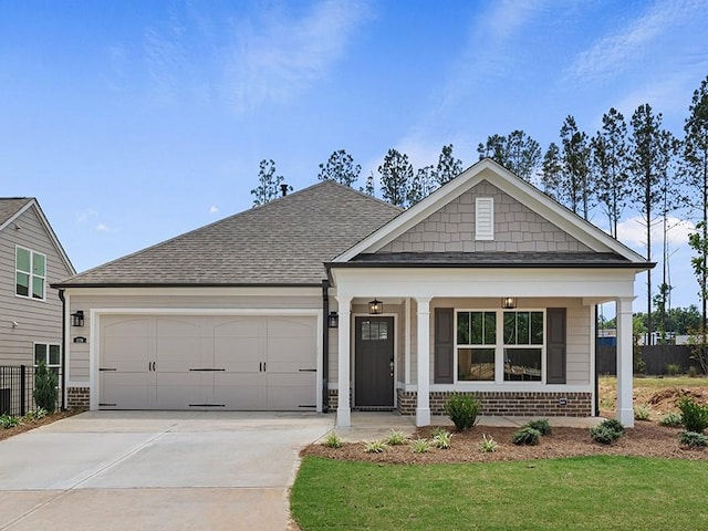 view of front of property with covered porch, a garage, and a front lawn