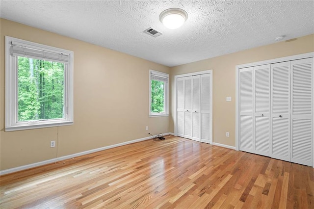 465 Willowbrook Dr SE, Smyrna, GA 30082 - unfurnished bedroom with multiple closets, light wood-style floors, baseboards, and a textured ceiling