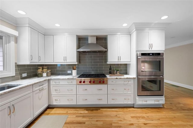 465 Willowbrook Dr SE, Smyrna, GA 30082 - kitchen with appliances with stainless steel finishes, wall chimney range hood, white cabinets, light wood finished floors, and baseboards
