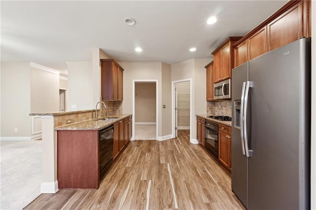 kitchen featuring sink, stainless steel appliances, tasteful backsplash, light stone counters, and kitchen peninsula