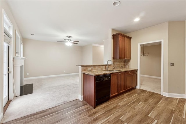 kitchen featuring dishwasher, ceiling fan with notable chandelier, sink, light stone countertops, and wood-type flooring