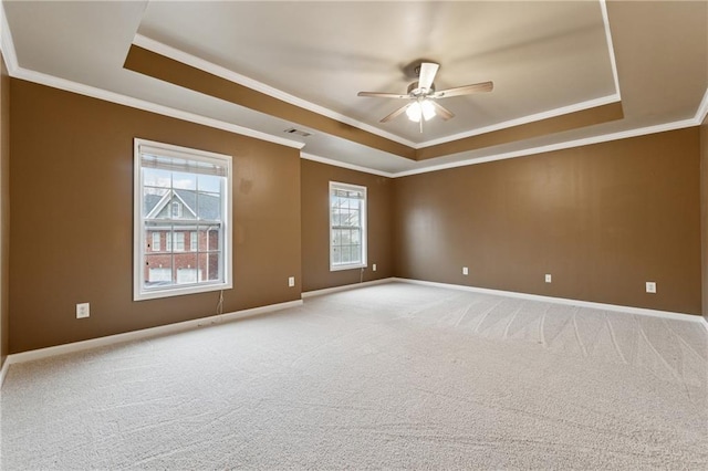 carpeted spare room featuring ceiling fan, ornamental molding, and a tray ceiling