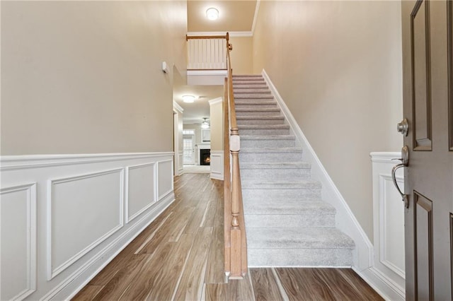 stairs with wood-type flooring and crown molding